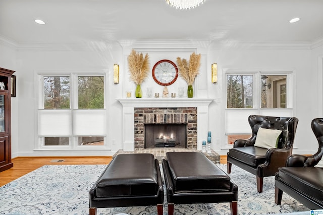 sitting room with light wood-type flooring, a brick fireplace, and ornamental molding