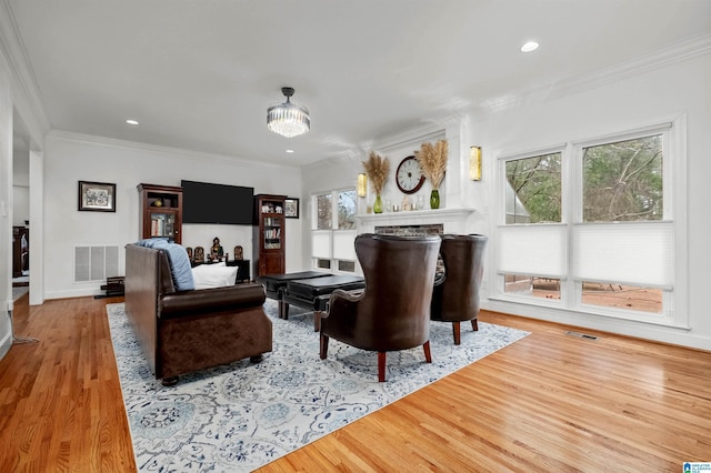 living room featuring light hardwood / wood-style floors, a stone fireplace, and ornamental molding