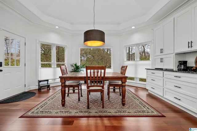 dining area with dark wood-type flooring, a raised ceiling, and recessed lighting