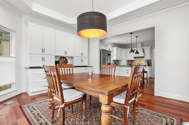 dining room featuring hardwood / wood-style flooring, a tray ceiling, and ornamental molding