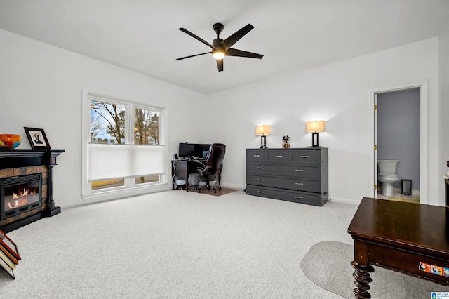 home office with carpet floors, a glass covered fireplace, a ceiling fan, and baseboards