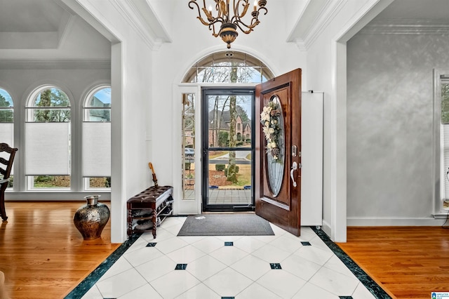 foyer with tile patterned floors, a notable chandelier, ornamental molding, and a wealth of natural light