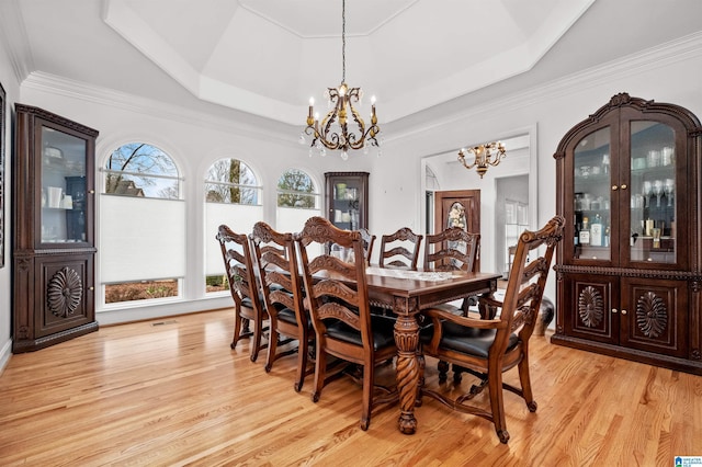 dining room featuring a notable chandelier, light hardwood / wood-style floors, crown molding, and a tray ceiling