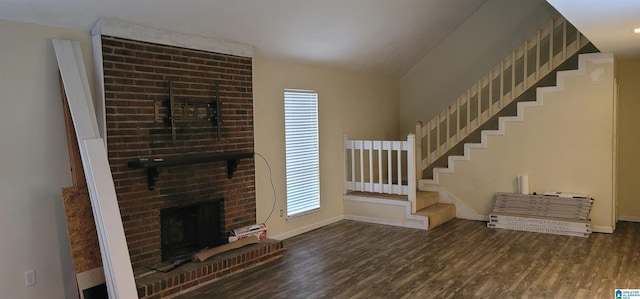 unfurnished living room featuring dark wood-type flooring and a brick fireplace