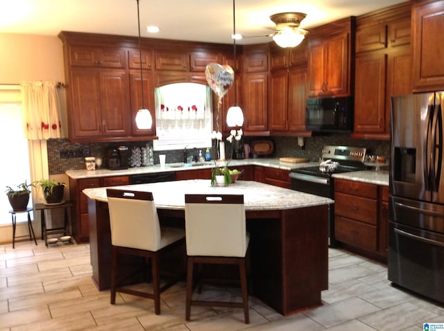 kitchen with a kitchen bar, sink, black appliances, decorative light fixtures, and a kitchen island