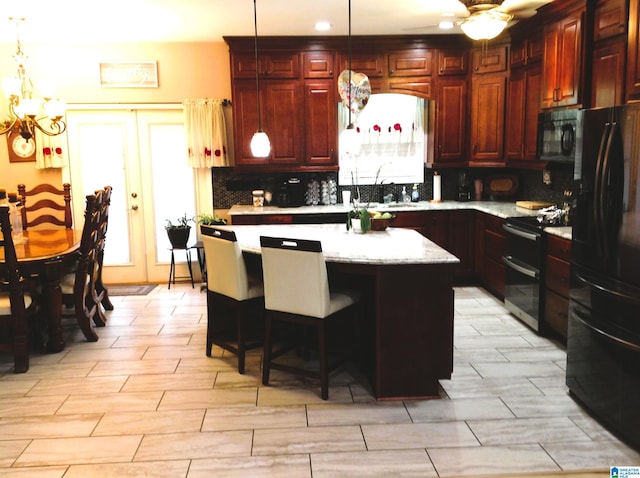 kitchen featuring hanging light fixtures, a breakfast bar, a center island, and black appliances