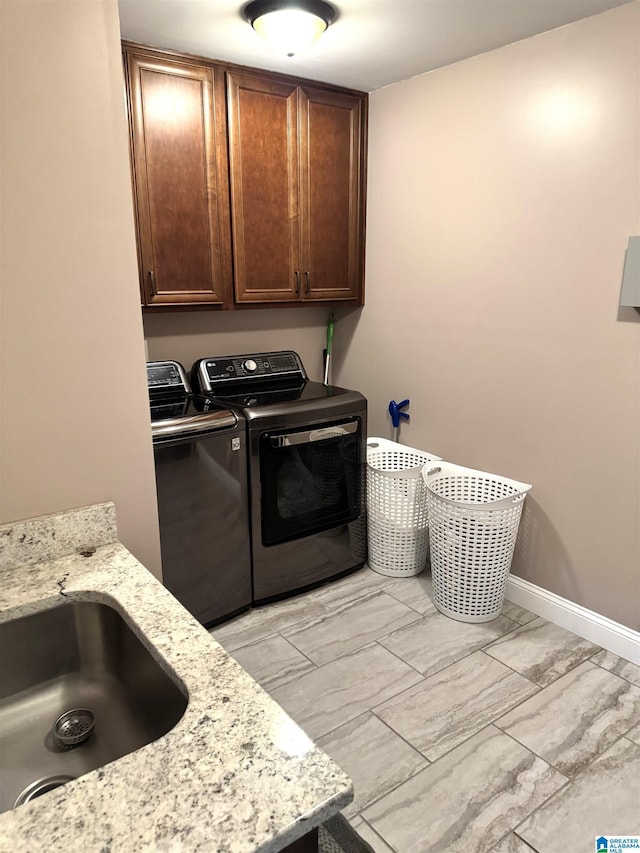 washroom with cabinets, washer and dryer, and sink