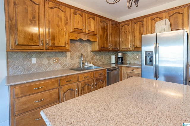 kitchen with appliances with stainless steel finishes, backsplash, light stone counters, and sink