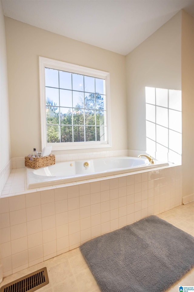 bathroom with tile patterned flooring and a relaxing tiled tub