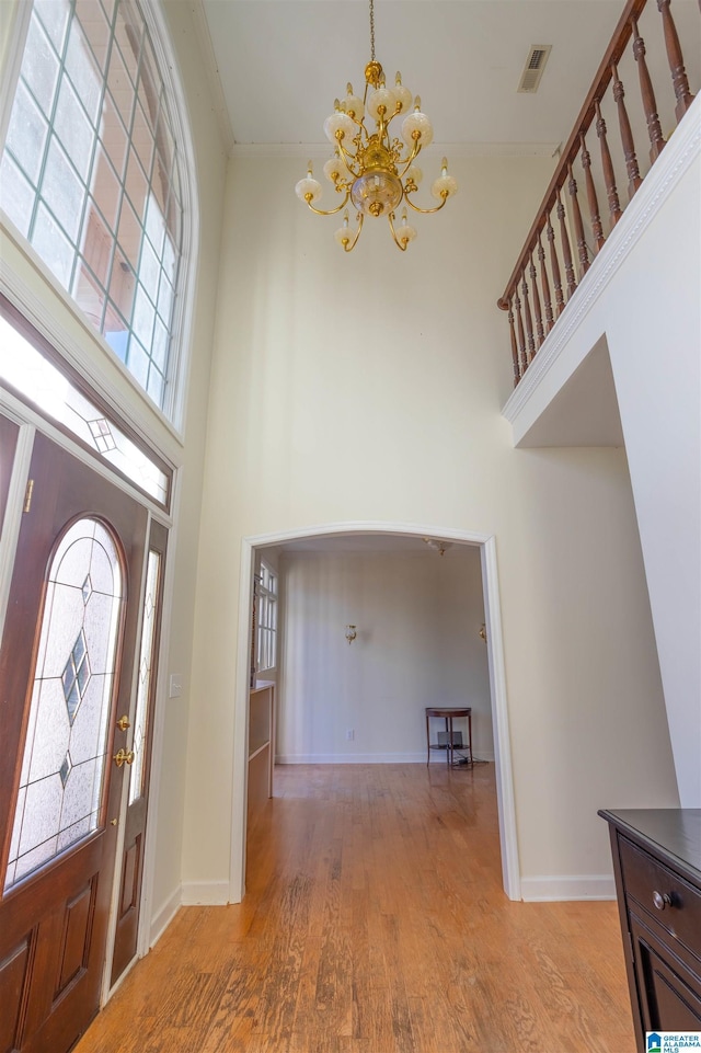 entrance foyer with a towering ceiling, light hardwood / wood-style floors, and an inviting chandelier