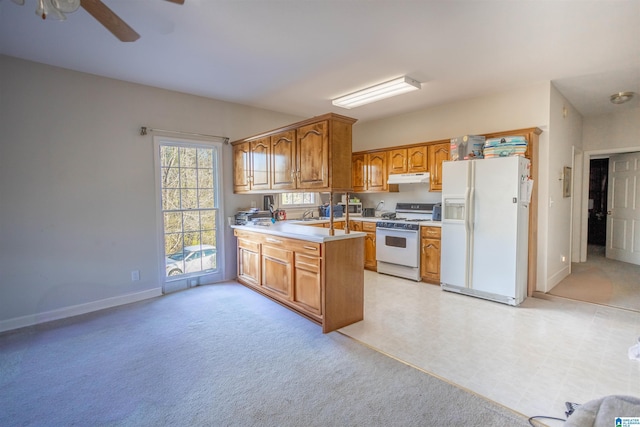 kitchen featuring white appliances, sink, ceiling fan, light colored carpet, and kitchen peninsula