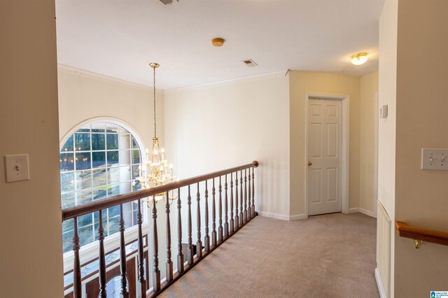 corridor with a notable chandelier, ornamental molding, and light carpet