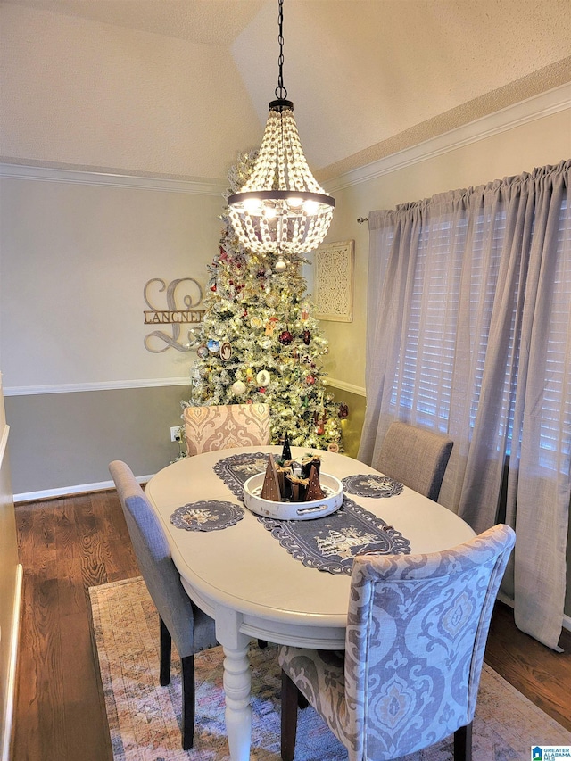 dining space featuring dark hardwood / wood-style floors, lofted ceiling, ornamental molding, and an inviting chandelier