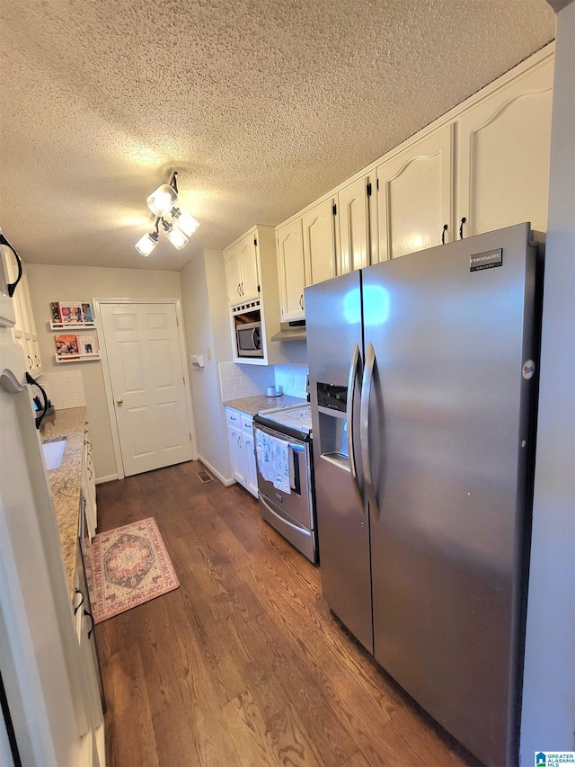 kitchen with dark hardwood / wood-style floors, light stone countertops, a textured ceiling, white cabinetry, and stainless steel appliances