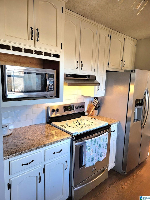 kitchen with dark hardwood / wood-style flooring, backsplash, dark stone counters, stainless steel appliances, and white cabinets