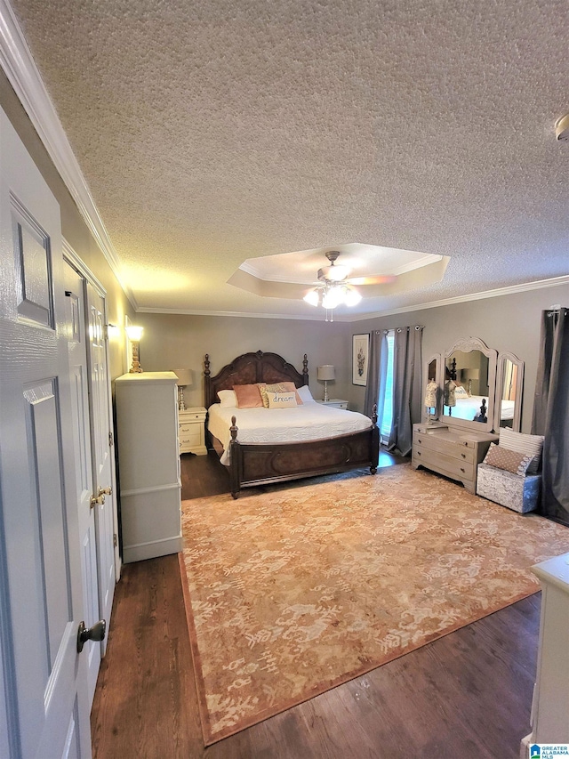 bedroom featuring a tray ceiling, ceiling fan, crown molding, and dark wood-type flooring