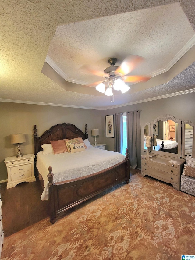 bedroom featuring a raised ceiling, hardwood / wood-style flooring, ceiling fan, ornamental molding, and a textured ceiling