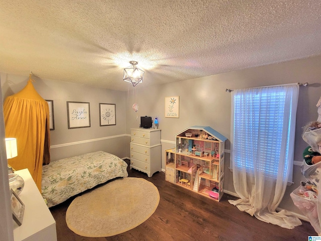 bedroom with dark hardwood / wood-style flooring, a textured ceiling, and multiple windows