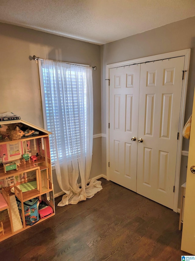 bedroom with a textured ceiling, dark wood-type flooring, and a closet