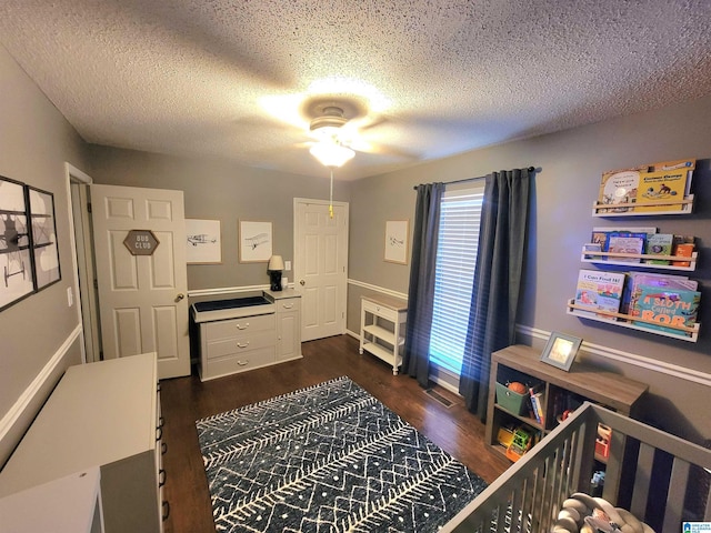 bedroom with a textured ceiling, ceiling fan, and dark hardwood / wood-style floors