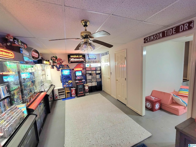 rec room featuring concrete floors, a drop ceiling, and ceiling fan