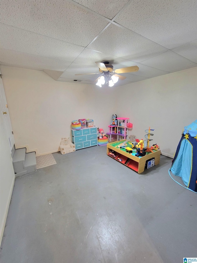 game room featuring a drop ceiling, ceiling fan, and concrete floors