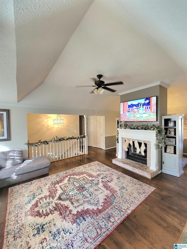 living room featuring ornamental molding, a textured ceiling, ceiling fan, dark wood-type flooring, and a fireplace