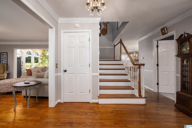 staircase featuring hardwood / wood-style flooring, crown molding, and a notable chandelier