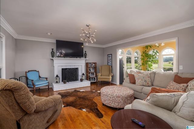 living room with a notable chandelier, wood-type flooring, a fireplace, and ornamental molding