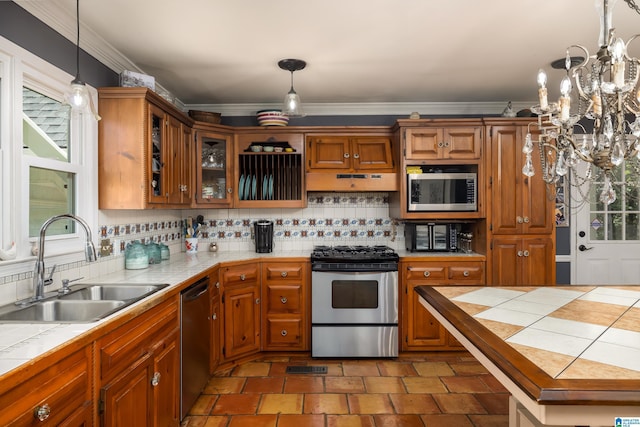 kitchen featuring an inviting chandelier, sink, decorative light fixtures, tile counters, and stainless steel appliances