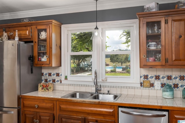 kitchen with tile countertops, crown molding, sink, and appliances with stainless steel finishes