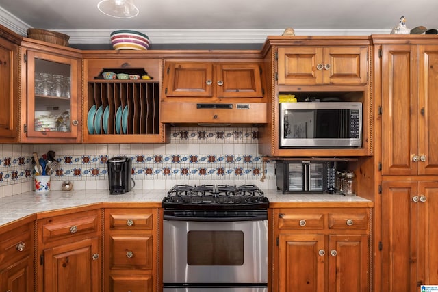 kitchen featuring tile countertops, decorative backsplash, stainless steel appliances, and ornamental molding