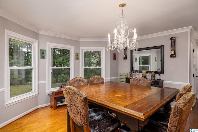 dining space featuring a healthy amount of sunlight, ornamental molding, light hardwood / wood-style flooring, and an inviting chandelier