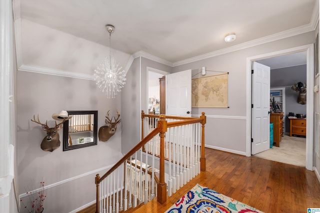 corridor featuring hardwood / wood-style flooring, an inviting chandelier, and ornamental molding