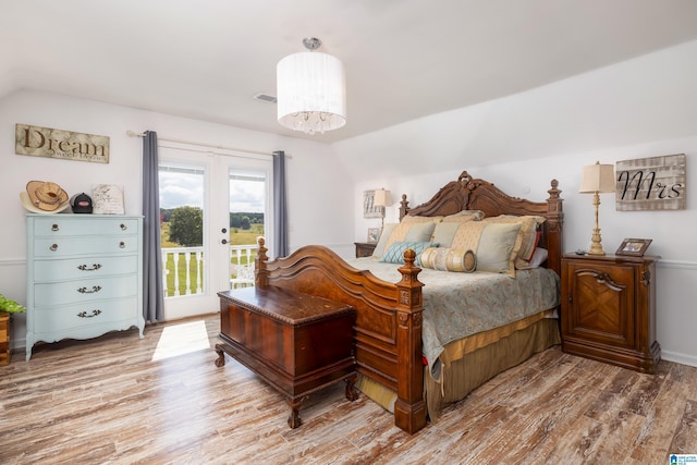 bedroom with access to outside, french doors, vaulted ceiling, wood-type flooring, and a chandelier