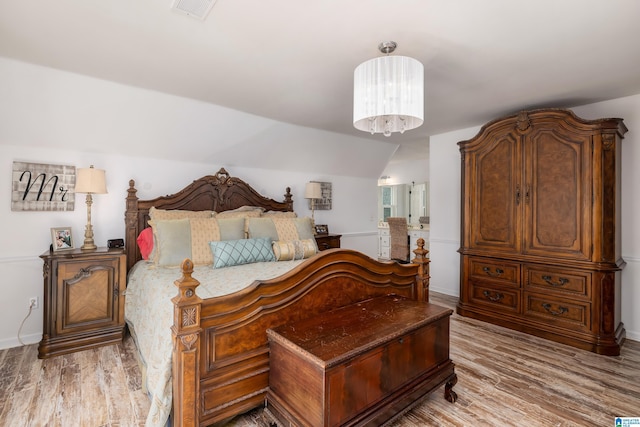 bedroom with vaulted ceiling and light hardwood / wood-style flooring