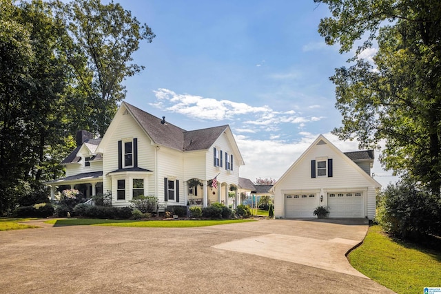 view of front of home with a porch, a front yard, an outdoor structure, and a garage