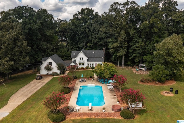 view of swimming pool featuring a yard, a patio, and a diving board