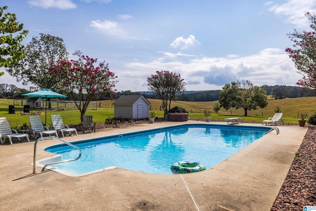 view of pool featuring a patio area, a yard, and a storage shed