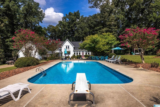 view of swimming pool with a diving board, a patio area, and a lawn