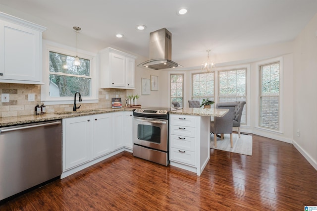 kitchen with stainless steel appliances, extractor fan, sink, white cabinetry, and hanging light fixtures