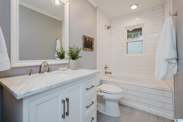 full bathroom featuring vanity, tiled shower / bath combo, toilet, ornamental molding, and wood-type flooring