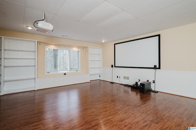 home theater featuring built in shelves, a paneled ceiling, and dark hardwood / wood-style floors