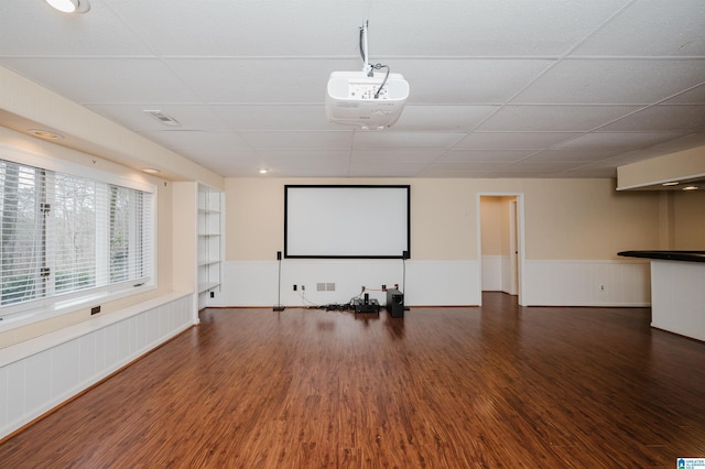 cinema with a paneled ceiling and dark wood-type flooring