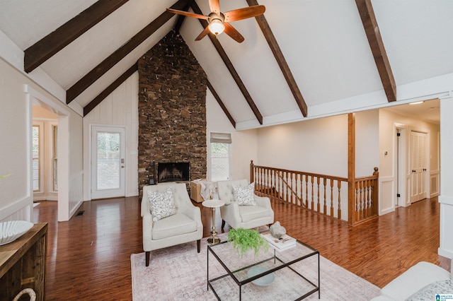 living room with beam ceiling, a stone fireplace, high vaulted ceiling, and dark hardwood / wood-style floors