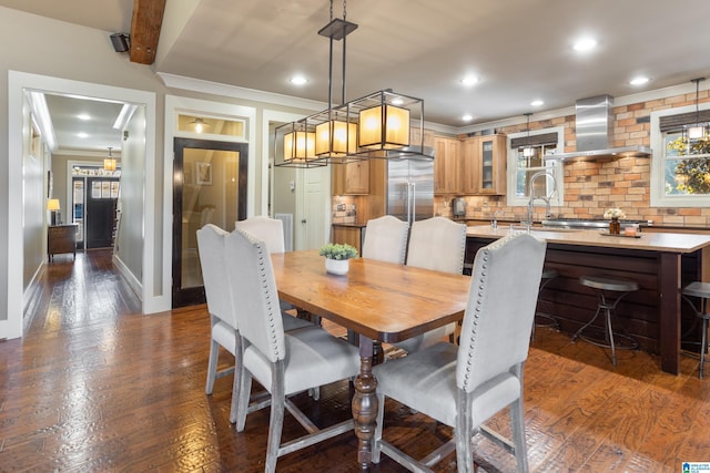 dining area with beamed ceiling, dark hardwood / wood-style floors, and sink