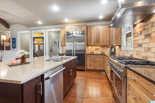 kitchen featuring sink, light stone counters, an island with sink, high quality appliances, and exhaust hood