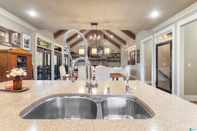 kitchen with sink, an inviting chandelier, vaulted ceiling with beams, light stone counters, and pendant lighting