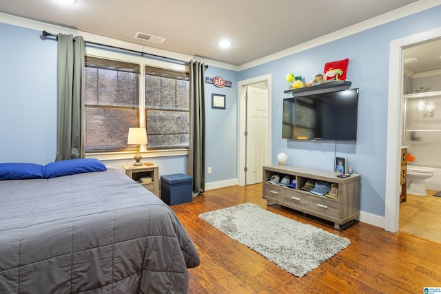 bedroom featuring connected bathroom, dark hardwood / wood-style floors, and ornamental molding