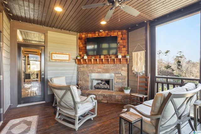 sunroom / solarium featuring ceiling fan, wood ceiling, and an outdoor stone fireplace